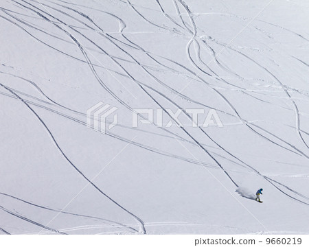 Snowboarder downhill on off piste slope with newly-fallen snow 9660219
