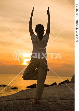 female yoga silhouette  on beautiful beach during sunset 9670341