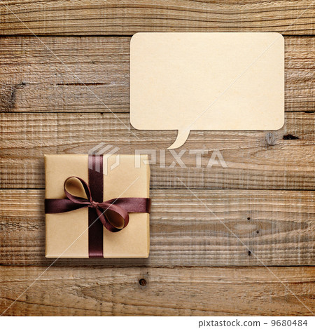 Gift box and speech bubble on wooden background Gift box and speech bubble on wooden background 9680484