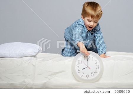 Little boy in blue pyjamas with clock 9689630