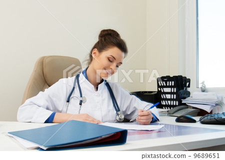 Cheerful young doctor woman in her office behind table 9689651
