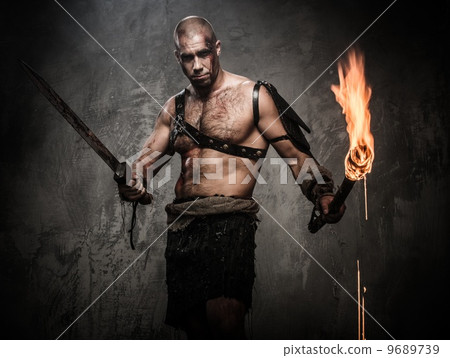 Wounded gladiator holding torch and sword covered in blood 9689739