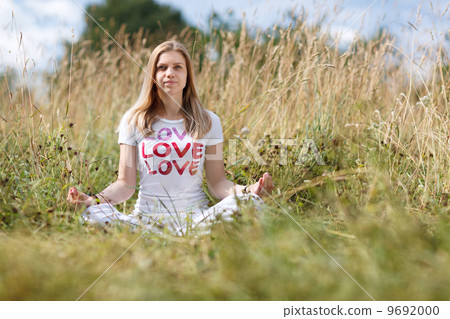 Young girl meditating in the field 9692000