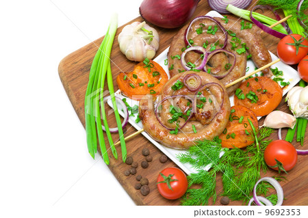 grilled sausages and vegetables on a cutting board on a white ba 9692353