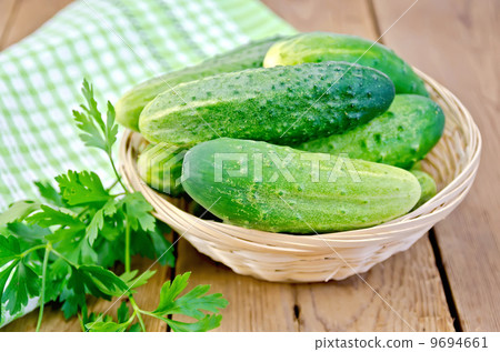 Cucumbers with parsley in wicker basket on a board Cucumbers with parsley in wicker basket on a board 9694661