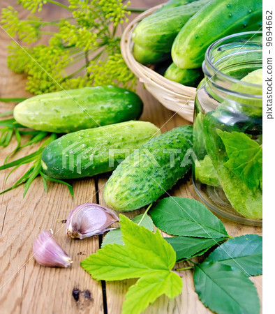 Cucumbers in jar and a wicker basket with leaves 9694662