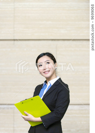 Business woman outdoor holding paper pad holder in front of marble wall 9699068