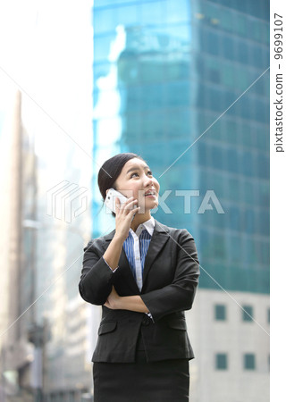 Business woman outdoor using mobile phone in front of glass building shallow depth of field 9699107