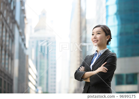Successful business woman outdoor folding arms in front of glass building shallow depth of field Successful business woman outdoor folding arms in front of glass building shallow depth of field 9699175