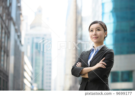 Successful business woman outdoor folding arms in front of glass building shallow depth of field Successful business woman outdoor folding arms in front of glass building shallow depth of field 9699177