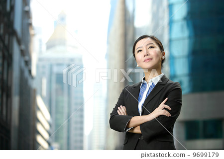 Successful business woman outdoor folding arms in front of glass building shallow depth of field 9699179