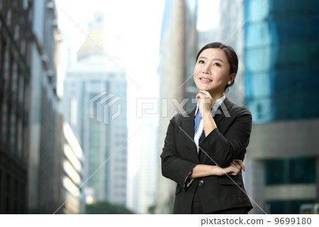 Successful business woman outdoor folding arms in front of glass building shallow depth of field 9699180