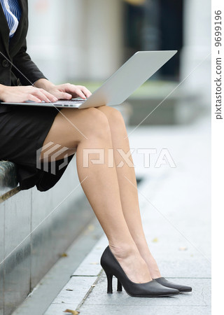 Successful petite business woman using laptop along promenade close up 9699196