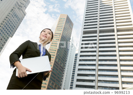 Successful business woman outdoor in front of building holding laptop  9699213