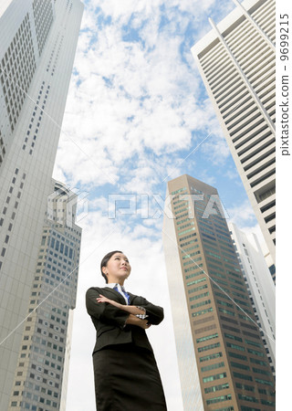 Successful business woman folding arms outdoor in front of building 9699215