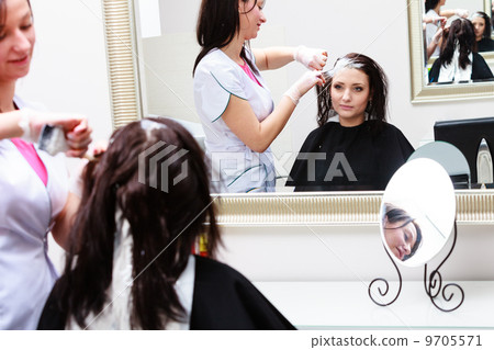 hairdresser applying color female customer at salon, doing hair dye 9705571