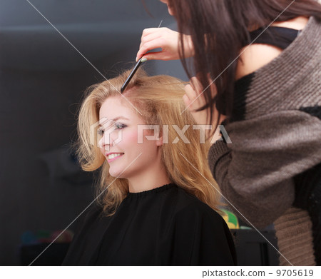 Hairstylist combing female client blond girl in hairdressing salon Hairstylist combing female client blond girl in hairdressing salon 9705619