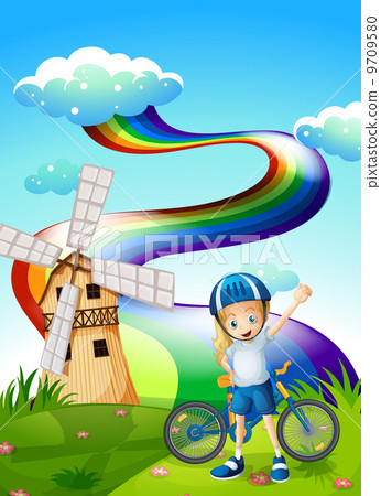 A young biker at the hilltop with a windmill and a rainbow A young biker at the hilltop with a windmill and a rainbow 9709580