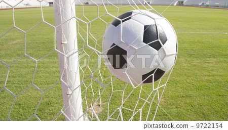 Soccer football in Goal net with green grass field 9722154