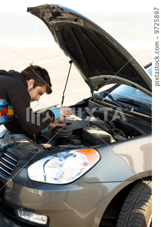 Car driver examining the car's engine 9725897
