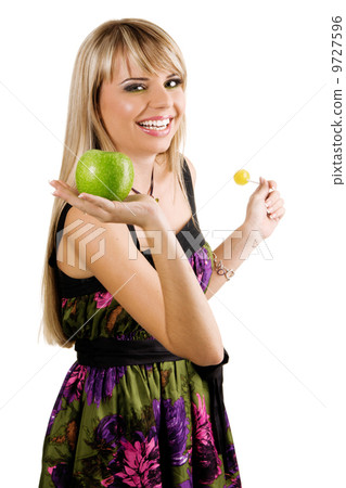Cheerful young woman holding fresh apple and lollipop 9727596
