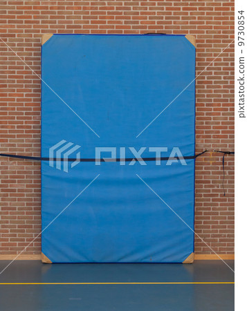 Large blue mat strapped to a brick wall Large blue mat strapped to a brick wall 9730854