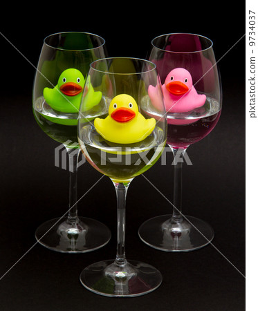 Green, yellow and pink rubber ducks in wineglasses 9734037