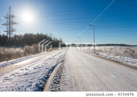 Sun on the electric power lines near road 9734976