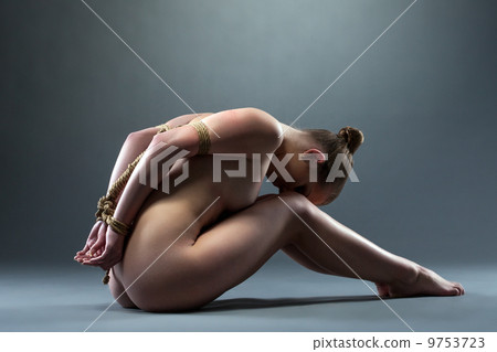 Side view of naked young woman tied with rope 9753723