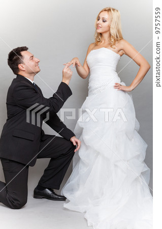 Groom putting a wedding ring on bride's finger Groom putting a wedding ring on bride's finger 9757559