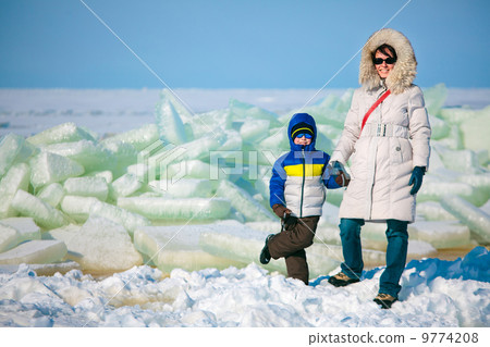 Young mother and her son on icy beach 9774208