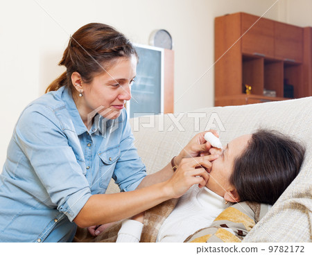 Adult daughter dripping collyrium to mother 9782172