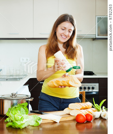 Happy girl cooking sandwiches with mayonnaise 9782263
