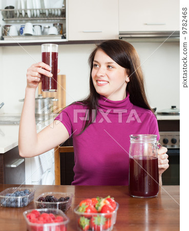 Happy woman making fresh beverages with berries Happy woman making fresh beverages with berries 9782468