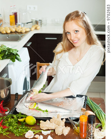 Happy woman cooking fish with lemon in sheet pan Happy woman cooking fish with lemon in sheet pan 9782683