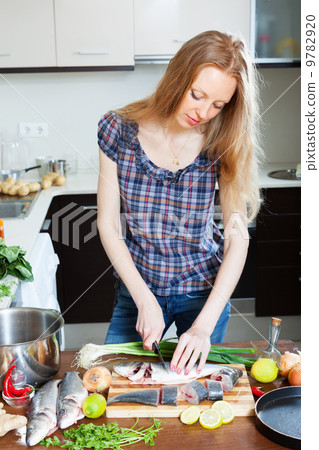Long-haired woman slicing raw saltwater fish Long-haired woman slicing raw saltwater fish 9782920