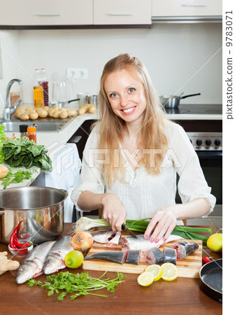housewife cooking fish at kitchen table housewife cooking fish at kitchen table 9783071