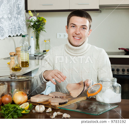 图库照片: happy handsome man cooking steak of porbeagle