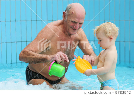 Sportive grandfather with grandchild having fun together playing in swimming pool Sportive grandfather with grandchild having fun together playing in swimming pool 9783942