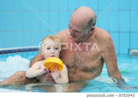 Sportive grandfather with grandchild having fun together playing in swimming pool  9783943