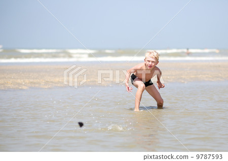 Happy teenager boy plays with the stones on the beach enjoying sun and the sea Happy teenager boy plays with the stones on the beach enjoying sun and the sea 9787593