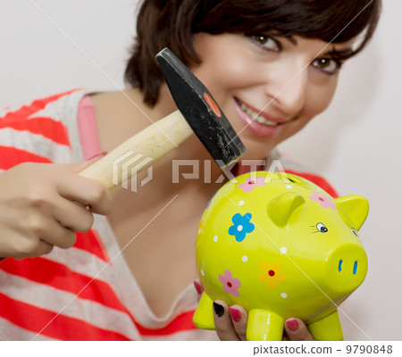 Young woman breaks a porcelain piggy bank with a hammer Young woman breaks a porcelain piggy bank with a hammer 9790848
