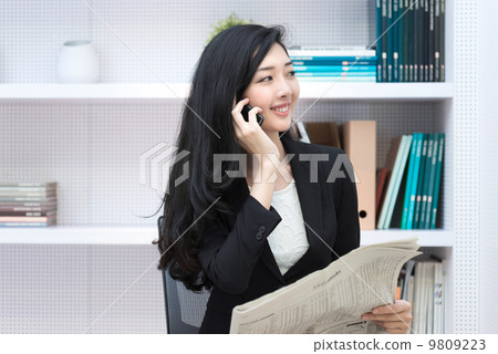 Young business woman in office making call reading newspaper Young business woman in office making call reading newspaper 9809223