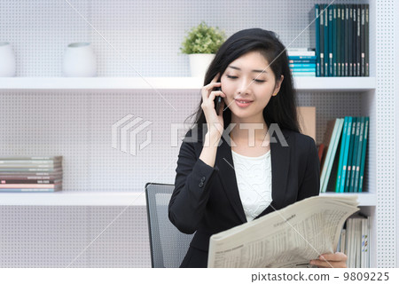 Young business woman in office making call reading newspaper  9809225