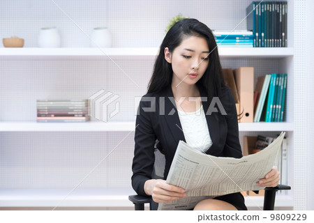 Young business woman in office reading newspaper Young business woman in office reading newspaper 9809229