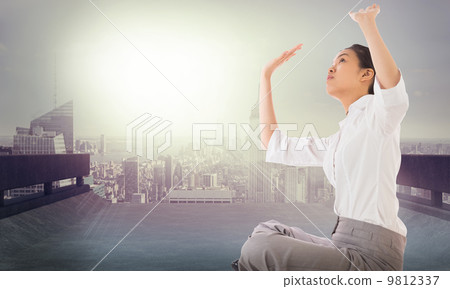 Composite image of businesswoman sitting cross legged pushing up 9812337