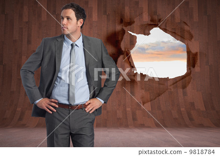 Composite image of serious businessman with hands on hips 9818784