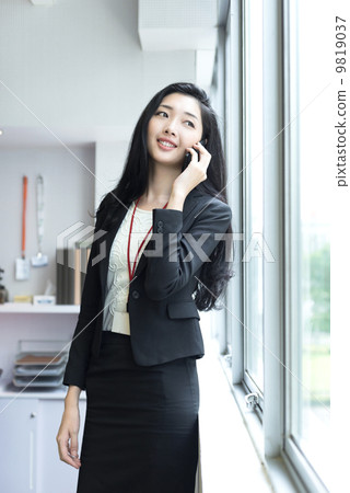 Young business woman using mobile phone outside office cubicle 9819037