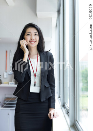 Young business woman using mobile phone outside office cubicle 9819039
