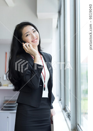 Young business woman using mobile phone outside office cubicle 9819040